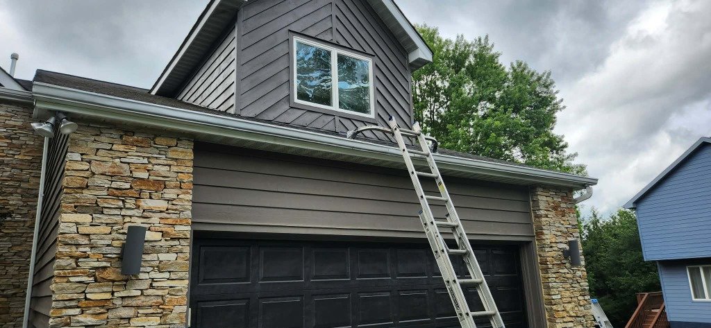 Gutter installation on gray home with stone facade